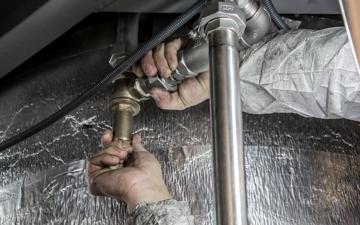 Technician kneeling at a water loss, inspecting the source